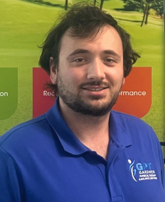 Evan Bier, PTA at Gardner Physical Therapy, standing in front of the sports medicine display promoting injury prevention and athletic performance.