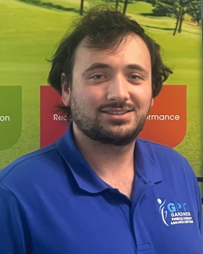 Evan Bier, PTA at Gardner Physical Therapy, standing in front of the sports medicine display promoting injury prevention and athletic performance.