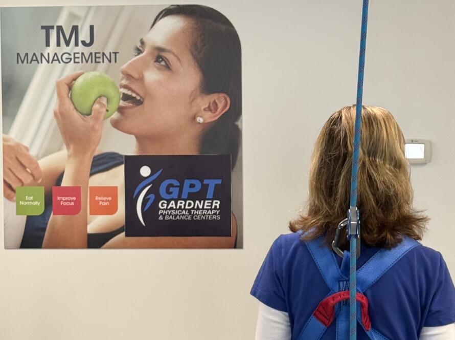 Back view of a patient using the Solo-Step harness and overhead track for supported gait training and fall prevention.