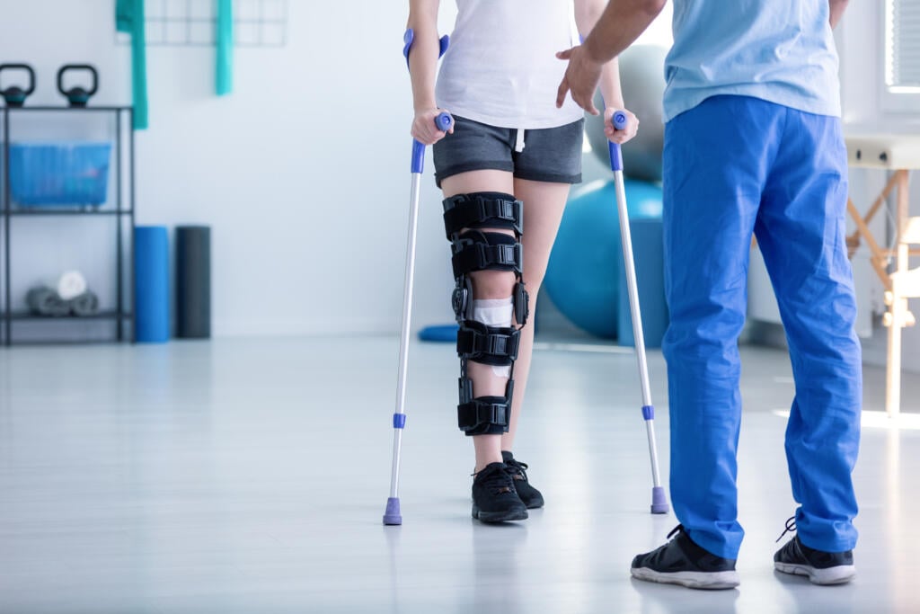 Professional,Physiotherapist,Supporting,Patient,With,Orthopedic,Problem - Gardner Physical Therapy Physical therapist guiding patient through resistance band leg exercise for balance and strength training in post-concussion rehabilitation at Gardner Physical Therapy.