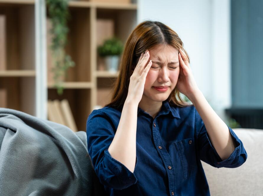 Young woman holding her head in pain, showing common concussion or post-concussion symptoms.