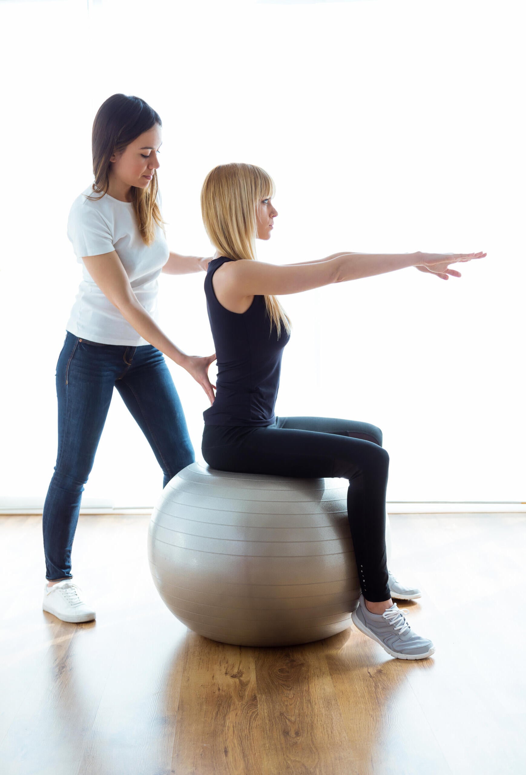 Ocean Pines physical therapist guides woman on stability ball to improve posture and core strength.