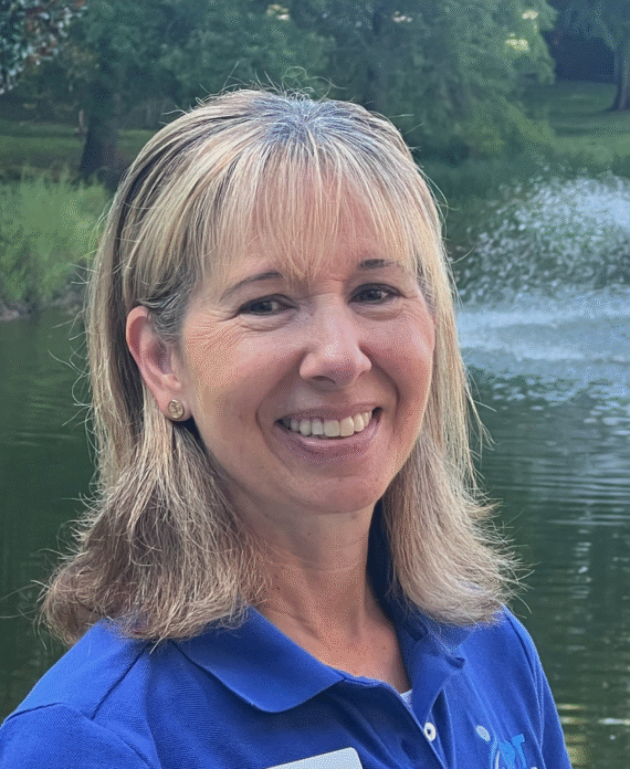 Mary Beth Gardner, PT, smiling outside near a fountain, representing Gardner Physical Therapy’s Ocean Pines location.