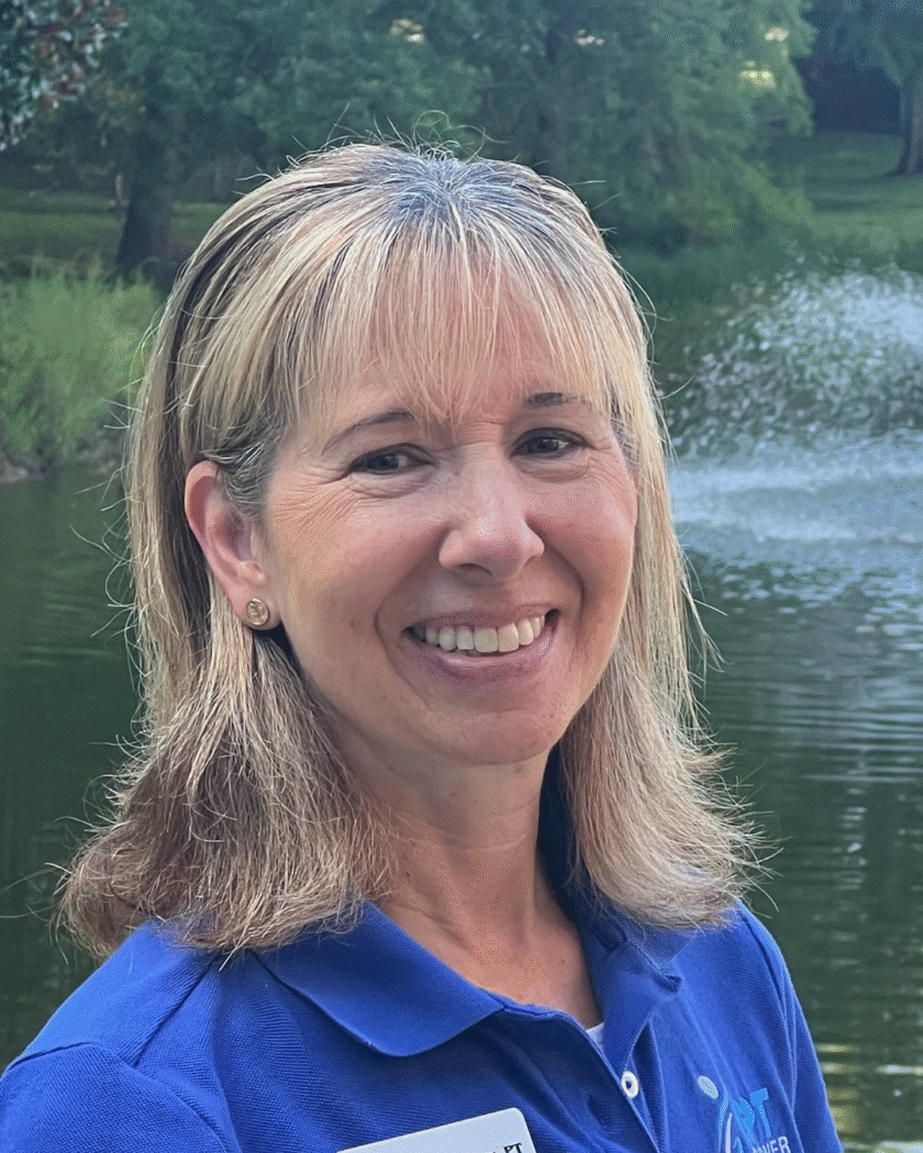 Mary Beth Gardner, PT, smiling outside near a fountain, representing Gardner Physical Therapy’s Ocean Pines location.