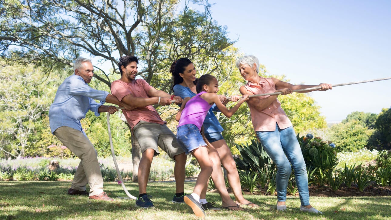 Family of multiple generations playing tug-of-war outdoors, promoting active living with Urinary Incontinence Gardner Physical Therapy.