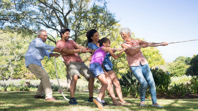 Family of multiple generations playing tug-of-war outdoors, promoting active living with Urinary Incontinence Gardner Physical Therapy.