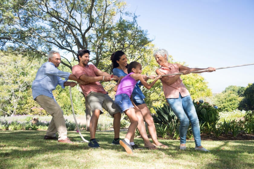 Family of multiple generations playing tug-of-war outdoors, promoting active living with Urinary Incontinence Gardner Physical Therapy.