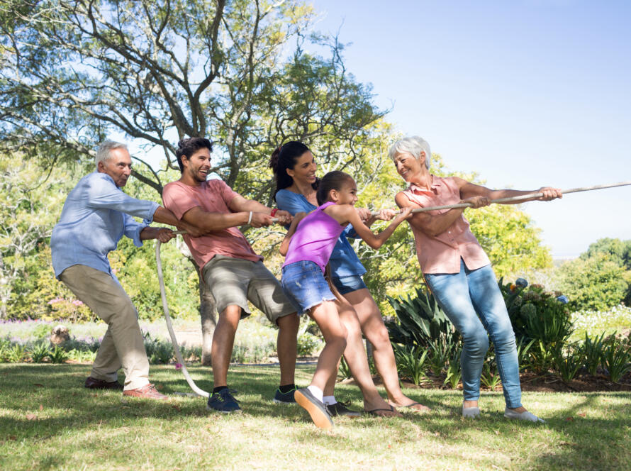 Family of multiple generations playing tug-of-war outdoors, promoting active living with Urinary Incontinence Gardner Physical Therapy.