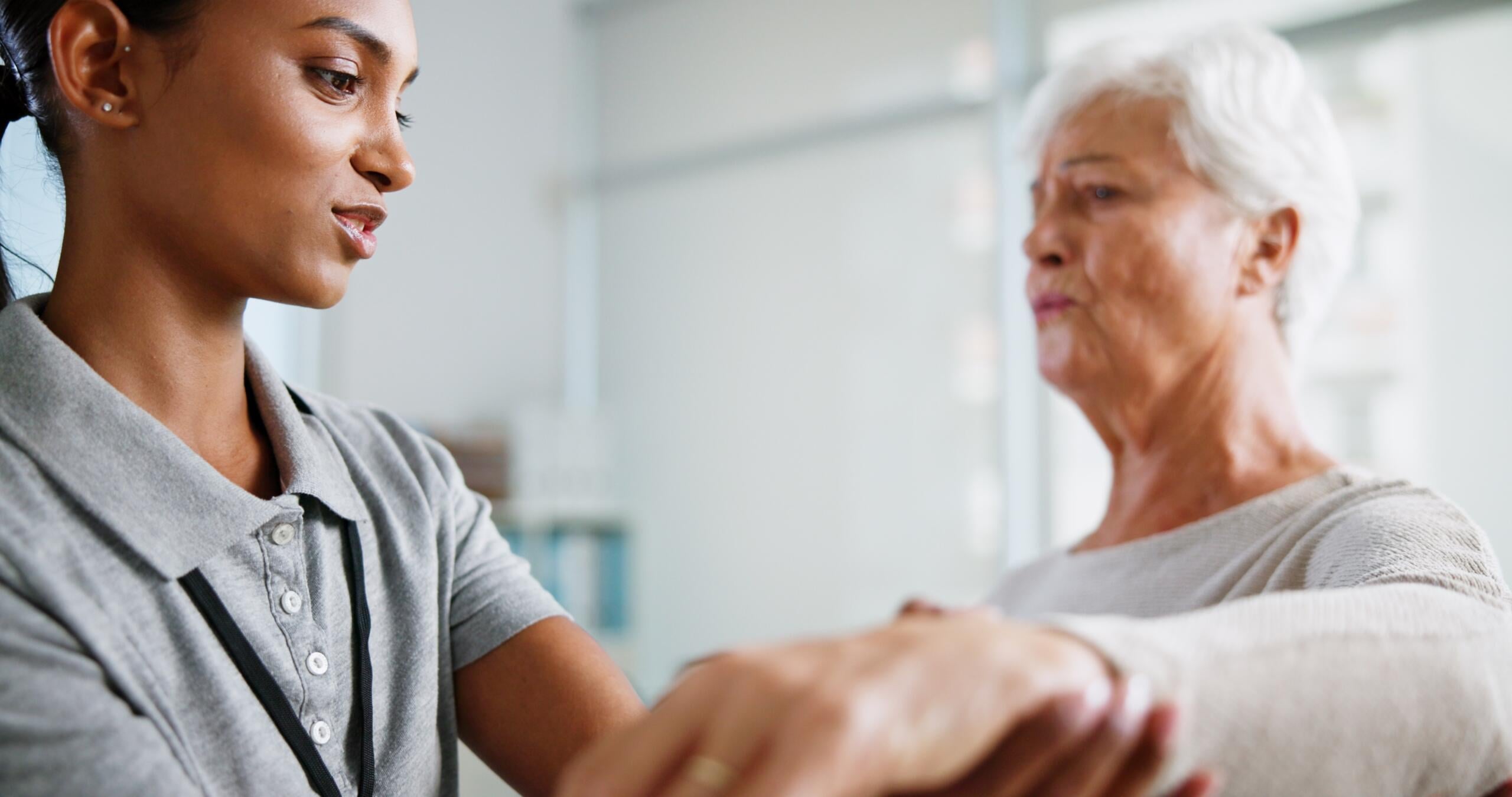 Gardner Physical Therapy provider assisting a senior patient with arm mobility exercises in a supportive rehab environment.