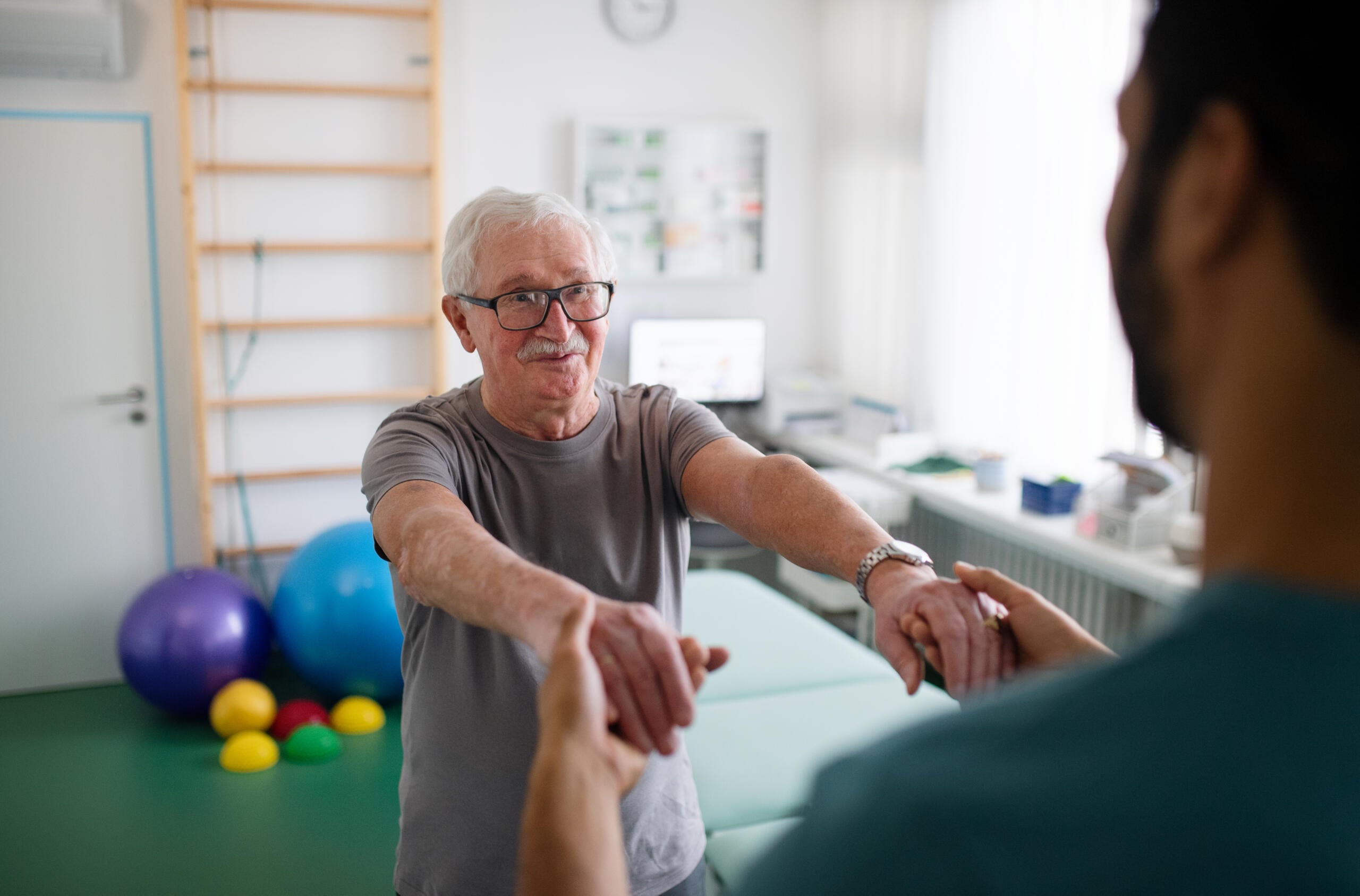Senior patient practicing guided arm mobility at Physical Therapy Glen Burnie.